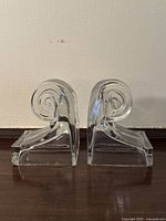 Front view of the pair of clear pressed glass book ends with spiral curl design, showing overall shape and size.