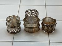Six assorted napkin rings arranged side by side on tile surface