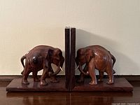 Front view showing both elephant bookends facing each other on their sturdy rectangular bases with vertical panels for book support.