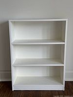 Front view of the white 3-shelf wooden bookcase showing all shelves.
