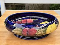 Side view showing red plum and yellow lemon motifs on cobalt blue exterior