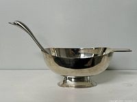 Silver plated gravy boat with matching swan neck ladle, side view showing the boat shape and handle