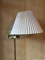Single lamp in profile with shade attached and arm extended against wood background