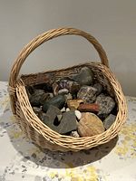 Front angle of a natural wicker basket filled with various rocks and minerals, showing the size and contents clearly.