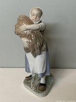Front view of Royal Copenhagen porcelain figurine showing girl holding wheat sheaf with detailed facial expression and attire.