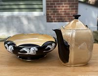 Both teapot and bowl visible on wooden surface outdoors, showing the shape and color of both porcelain pieces