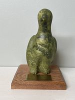 Front view of green soapstone bird sculpture on oak base showing brass plaque
