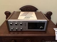Full front view of the Muntz 5000 stereo receiver with the manual on top