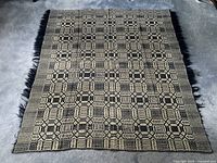 Full view of the vintage navy and cream geometric woven coverlet blanket, showing its full size and fringe edges.