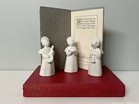 Three small Royal Copenhagen porcelain angels on top of the 1948 Santa Claus Book with the Victorian poem The Snow Fairies card behind them.