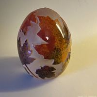 Full view of egg-shaped frosted glass paperweight with maple leaf motifs