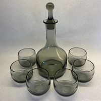 full view of decanter with stopper surrounded by six glasses