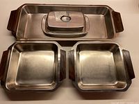 All five stainless steel pieces visible: long platter, butter dish with lid, two square dishes