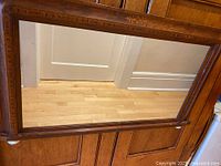 Full view of rectangular mirror displaying wood frame, inlay, and ceramic feet