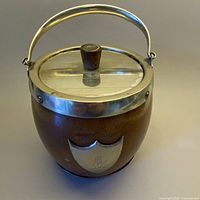 Full view showing wooden vessel with metal lid and handle