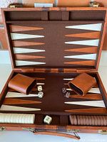 Open case showing board surface, checkers stacked, dice cups, dice, doubling cube