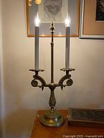 Full view of brass two-arm candelabra lamp with bulbs lit