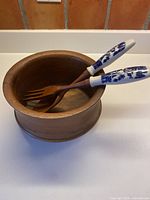 Teak bowl with spoon and fork resting inside