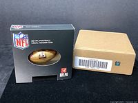 Photo of the original boxed packaging showing NFL and NFLPA logos and the coin visible through a window.
