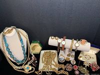 Wide shot of assorted vintage costume jewelry including necklaces, watches, pendants, and brooches.