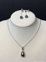 Full set of necklace with pendant and pair of earrings displayed on jewelry bust.