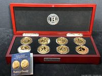 Full view of the 8 gold plated JFK proof coins in the wood display box along with certificate of authenticity booklet.