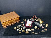 Overview of all items in the lot including wooden box and various pins, coins, clasps and buttons.