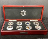 Full open wooden display box showing 8 cased silver plated coins with color portraits and inscriptions in protective plastic capsules.
