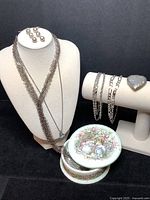 Overall lot view showing all jewelry displayed on stands and the porcelain trinket box with lid placed on box base revealing interior