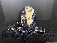 Set of four items: metal collar necklace displayed on a bust with navy blue silk scarf beneath it, silver bead bracelet arranged on bust, earrings hanging, and scarf partially shown with fringed edges.