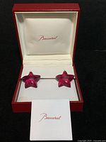 Pair of dark pink star crystal earrings with gold posts displayed in original red Baccarat box with white interior and Baccarat card.