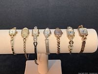 Seven gold-tone vintage ladies watches mounted on display stand