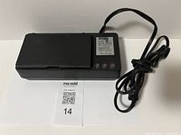 Top view of the black Pulser battery charger with hinged compartment, power cord, and three indicator lights.