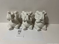 Front view of three white ceramic elephant figurines representing 'See No Evil, Hear No Evil, Speak No Evil'.