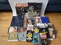 Overhead photo showing entire assortment of Elvis Presley items arranged on floor, including books, magazines, and CDs.