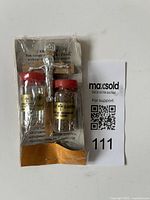 Photo of the religious keepsake set including two sealed vials and a metal crucifix in clear plastic packaging with card backing