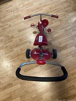 Top view of red Radio Flyer kids tricycle showing handlebar, seat, pedals, and push handle.