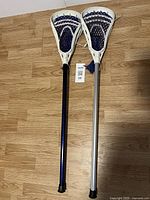 Two lacrosse sticks standing upright, showing shafts and heads with netting