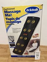 Front view of the Dr Scholl's cushioned massage mat box showing product image, brand, and features.