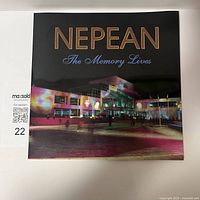 Front cover of a large square hardcover book titled 'NEPEAN The Memory Lives' featuring an illuminated modern building at night with colorful projections.