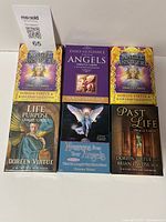 Six oracle card decks arranged with visible titles and artwork on box covers.