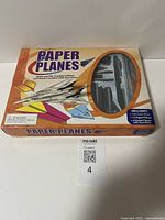 Front view of the Paper Planes box showing kit contents through window including paper planes and plastic model parts.