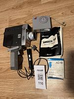 Overall lot showing Ricoh Singlex TLS camera, detachable flash, microphone, instruction manual, and flashbulbs on wooden floor.