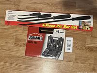 View of boxed 4-piece pry bar set and boxed Jobmate 44-piece tool set on floor.