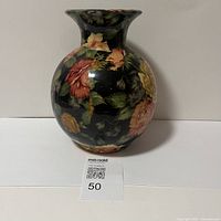 Front photo of a spherical ceramic vase featuring colorful roses and leaves on black background.