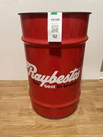 Front view of vintage Raybestos red metal oil drum can with white logo and black slogan 'The best in brakes'.