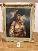 Frontal full view of the framed painting showing the gypsy lady portrait and frame with cardboard corner protectors.
