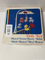 Box of the Dolly Toy's musical animal shower mobile showing colorful animals and umbrella canopy illustration.
