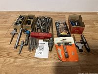 Full view of the vintage tools lot arranged on table showing various hand tool pieces, drill arbors, boxed parts, and packaged hex key set.