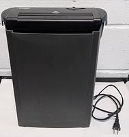 Full view of black paper shredder bin with power cord beside it.